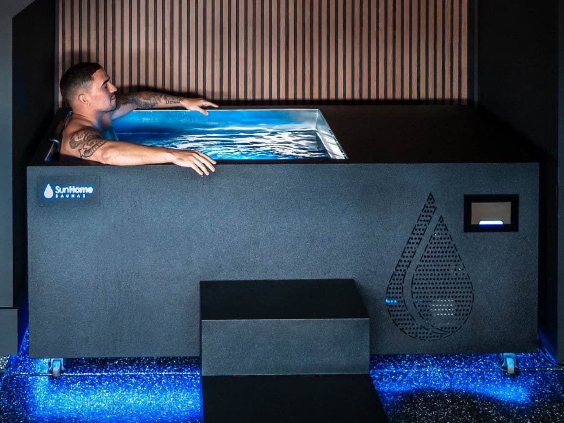 Sun Home Cold Plunge Pro: black hard-sided tub with integrated steps and stainless interior, with a person seated inside